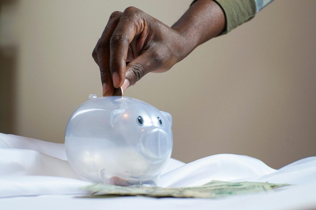 person putting coins in piggy bank