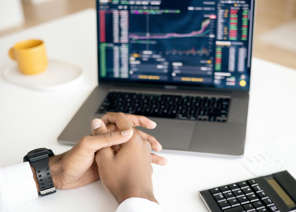 laptop showing stocks, crossed hands